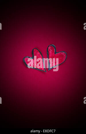 Zwei Herzen und Dunkelheit. Zwei rote Papier Herzen Form auf einem roten Hintergrund. Stockfoto