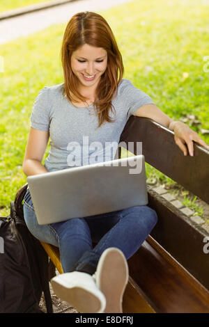 Glückliches Mädchen sitzen auf Bank mit laptop Stockfoto