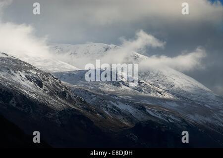 Eine Reihe von Bergen voller Schnee und Strähnen von Cloud, dunkle Wolke im Hintergrund. Stockfoto