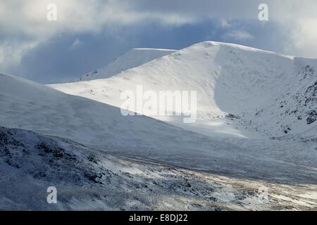 Eine Reihe von Bergen bedeckt im Schnee mit dunkle Wolke im Hintergrund. Stockfoto