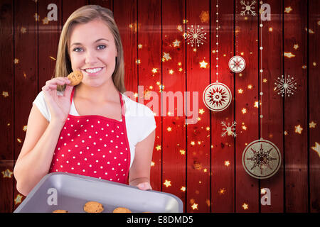 Zusammengesetztes Bild der hübschen Hausfrau zeigt heiße cookies Stockfoto