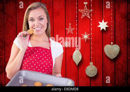 Zusammengesetztes Bild der hübschen Hausfrau zeigt heiße cookies Stockfoto