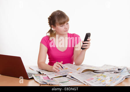 Ein junges Mädchen sitzt an einem Tisch mit einem Haufen von Zeitungen, Lexika und einen laptop Stockfoto