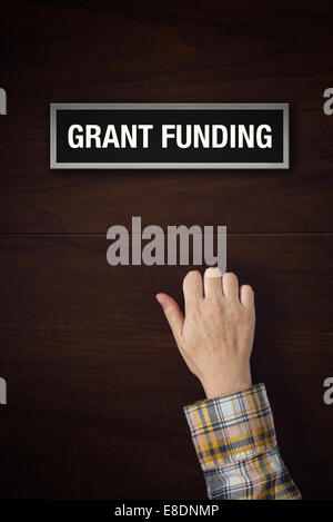 Weibliche Hand klopft an Grant Funding Tür, Konzeptbild. Stockfoto