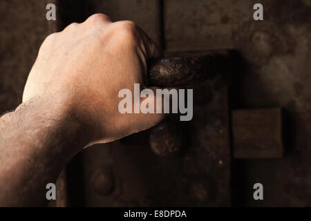 Männliche Hand ziehen Sie den Griff verrostet von alten Gefängnis Metalltür mit großen Schloss Stockfoto