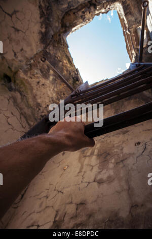 Trashigen Interieur mit alten Metallleiter, blauer Himmel im Ende und männliche Hand halten es Stockfoto