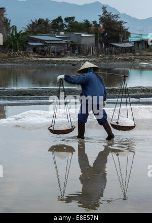 Eine Frau trägt zwei Körbe gefüllt mit frisch geerntete Salz auf ihrer Schulter-Pol. Stockfoto