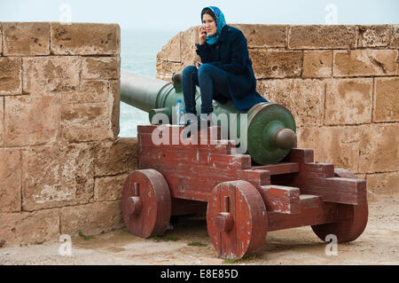 Horizontale Nahaufnahme einer muslimischen Frau sitzt auf einem Canon in Essaouira Stockfoto