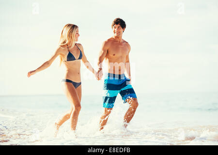 Attraktive glückliche Paar laufen und spielen am schönen Sonnenstrand Stockfoto