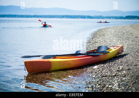 Orange und gelb Kajak auf dem Meer Küste während ein schöner Tag Sommer mit unkenntlich Menschen Kajak im Hintergrund Stockfoto