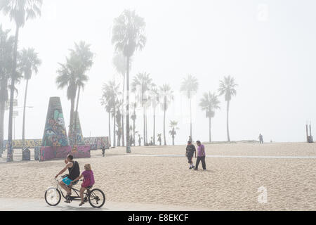 Ein paar mit dem Fahrrad für zwei gebaut und Passanten in den Sand an einem nebligen Morgen Stockfoto