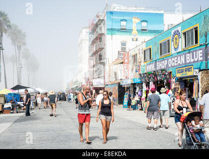 Shopper Venice Beach Boardwalk entlang, an einem nebligen Morgen mit Hochbau im Hintergrund Stockfoto