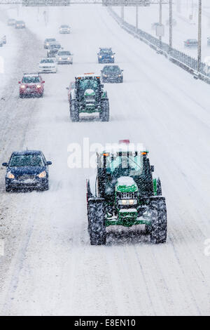 Zwei Schneepflüge und Autos auf der Autobahn während einem Schneesturm Wintertag Stockfoto