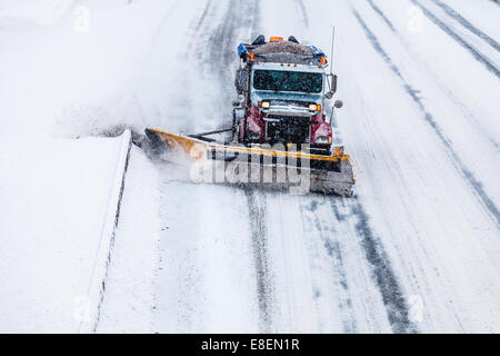 Schneepflug LKW entfernen den Schnee von der Autobahn in einem kalten Schneesturm Wintertag Stockfoto