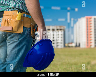 Nahaufnahme des männlichen Ingenieur mit blauen Bauarbeiterhelm, mit Bauten im Bau auf Hintergrund Stockfoto
