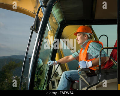 männliche Fahrer fahren Bagger auf Bau Baustelle Stockfoto