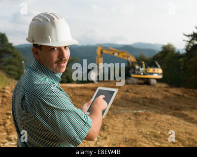 Porträt des jungen kaukasischen Ingenieur auf Baustelle mit digital-Tablette Stockfoto