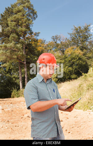 Seitenansicht des ständigen Ingenieur mit Tablet auf Baustelle im freien Stockfoto