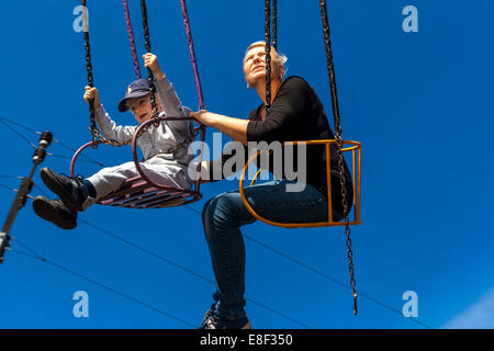 Aktives Altern, Leute an der Kette schaukeln Karussell, eine ältere Frau mit einem Enkel, Spaß Stockfoto