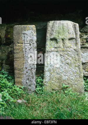 Str. Marys Abbey, Bardsey Island: Kreuz-geschnitzte Säule Grab Marker & Kreuz-Welle Fragment mit Unterteil der Figur trägt ein Plissee Kleid. Stockfoto