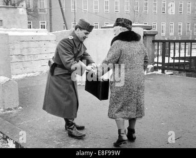 Ein freundliches Volk Polizist hilft einer älteren West-Berlin Frau, die die Pass-Kampagne 1963, an einem der fünf Grenzen verwendet, um ihre Verwandten in Ost-Berlin besuchen. Die Bundesrepublik Deutschland und der Deutschen Demokratischen Republik wurden durch einen Eisernen Vorhang vom 13. august 1961, der Tag der Gebäude der Berliner Mauer bis zum Fall der Berliner Mauer am 9. November 1989 aufgeteilt. Stockfoto