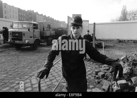 Ein ehemaliger Offizier der DDR-Grenze stellt bei einer vorläufigen Grenzübergang Eberswalder Straße, geöffnet, damit der Ostberliner in den Westen, Berlin, Deutschland, 13 November 13. November 1989 übergeben. Die Öffnung der Mauer wurde versehentlich auf einer Pressekonferenz von DDR-Beamten am 9. November 1989 erklärt, was in letzter Konsequenz bis zum Fall der Mauer und der Wiedervereinigung führte. Weitere Grenzübergänge entstanden die folgenden Tage. Foto: Eberhard Kloeppel Stockfoto