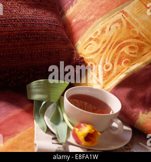 Nahaufnahme der Tasse Tee gegen Hand bemalte Kissen Stockfoto
