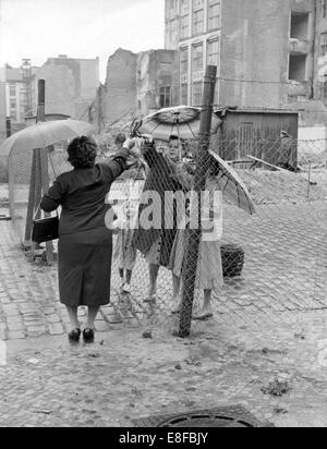 Eine Frau aus West-Berlin übergibt etwas über den Draht, der in der Zwischenzeit die beiden Teile der Stadt teilt, zu einer Familie in Ost-Berlin am 16. August 1961. Stockfoto