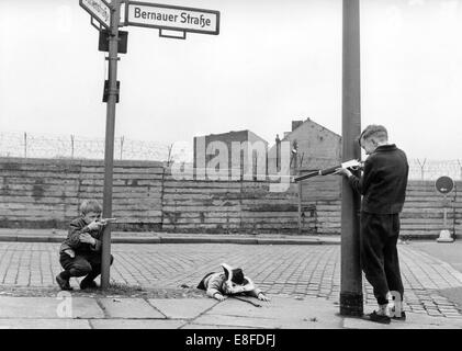 Drei kleine Jungs spielen mit Spielzeugpistolen vor Berliner Mauer in der Bernauer Straße am 13. Januar 1966. Stockfoto