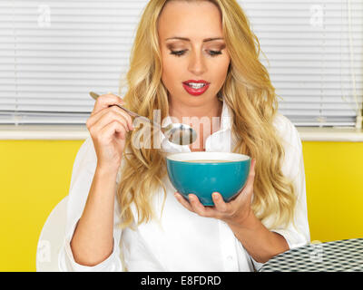 Sicher glückliche junge Frau, essen eine Schüssel mit frischem heißem nahrhafte Suppe, vor einem gelben Hintergrund Stockfoto