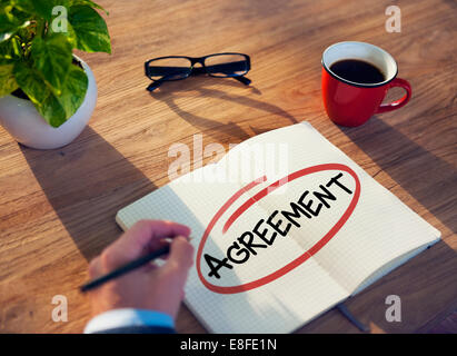 Hand mit eine Notiz und ein einziges Wort Abkommen Stockfoto