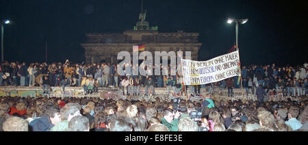 Einen Tag nach der Grenzöffnung feiern Tausende von Menschen auf, vor und hinter der Berliner Mauer am Brandenburger Tor in Berlin am 10. November 1989 (Westseite). Die innerdeutsche Grenze, die das Land seit 1961 praktisch getrennt hatte aufgehört zu existieren. Ein Plakat im Vordergrund des Bildes lautet: "für ein Berlin ohne eine Wand in ein Deutschland ohne Tanks in einem Europa ohne Grenzen". Foto: Peter Zimmermann Stockfoto