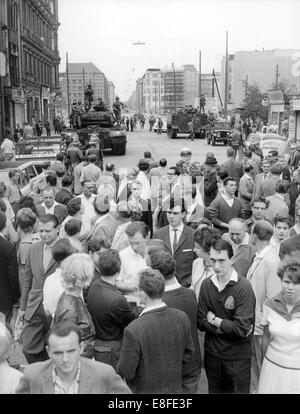 Am 27. august 1961 weiter viele West-Berliner Bürger den Kontrollpunkt Friedrichstraße während ihren Sonntagsspaziergang entlang der Flut, die vor kurzem von der Regierung gebaut wurde. Der Prüfpunkt, der Checkpoint Charlie später genannt wurde, sicherte sich schwere Patton-Panzer der US-Armee zu diesem Zeitpunkt. Vom 13. August 1961, der Tag der Errichtung der Mauer, waren bis zum Fall der Berliner Mauer am 9. November 1989 der Bundesrepublik und der DDR durch den "Eisernen Vorhang" zwischen Ost und West getrennt. Stockfoto