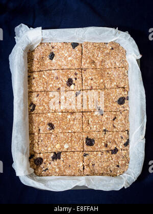 Hausgemachtem zäh Müsli (Müsli) Protein-Riegel von Erdnussbutter, Honig, Nüssen und Rosinen auf ein Backpapier gemacht. Ansicht von oben. Stockfoto
