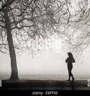 Silhouette einer Frau, die durch den Park läuft, England, Großbritannien Stockfoto