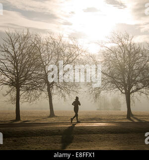 Silhouette einer Frau, die durch den Park läuft, England, Großbritannien Stockfoto