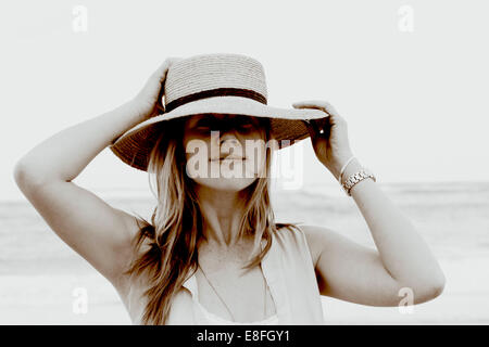 Porträt einer lächelnden Frau, die am Strand mit ihrem Hut steht, Südafrika