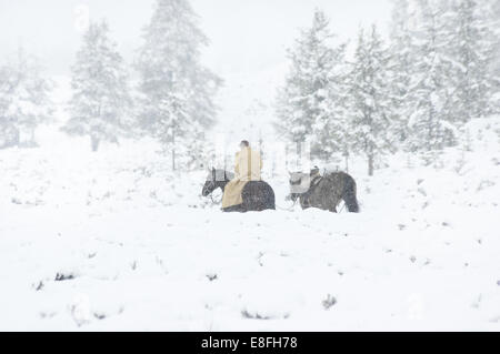 Cowboy auf einem Pferd im Schnee, Wyoming, USA Stockfoto