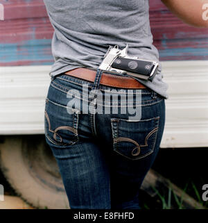 Frau mit einer Pistole in der Rückseite der Jeans versteckt Stockfoto
