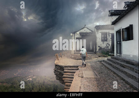 Mann, der die Straße entlang geht, mit einem Tornado, der sich nähert, Huangpu Bezirk, Shanghai, China Stockfoto