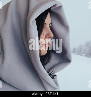 Porträt einer Frau, die im Schnee mit einem Kapuzenmantel steht, Calgary, Alberta, Kanada Stockfoto