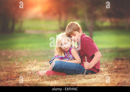 Junge und ein Mädchen sitzen in einem Park spielen, Kalifornien, USA Stockfoto