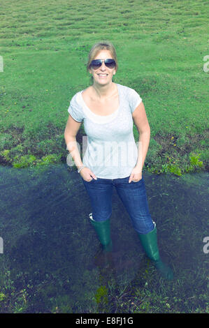 Porträt einer lächelnden Frau, die in einem Fluss, dem New Forest, Hampshire, England, Großbritannien, steht Stockfoto