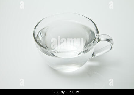 Teetasse aus Glas, gefüllt mit heißem Wasser auf weißem Hintergrund Stockfoto