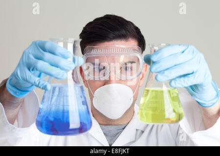 Wissenschaftler halten zwei konische Flaschen Stockfoto