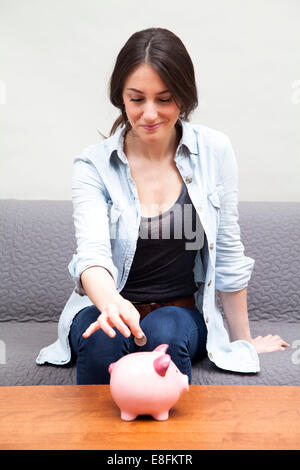 Frau, Münze ins Sparschwein Stockfoto