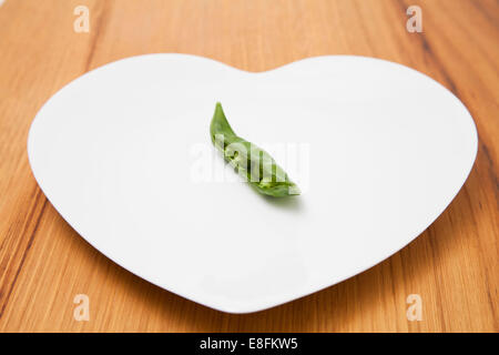 Nahaufnahme eines Erbsenbeins auf einem herzförmigen Teller Stockfoto