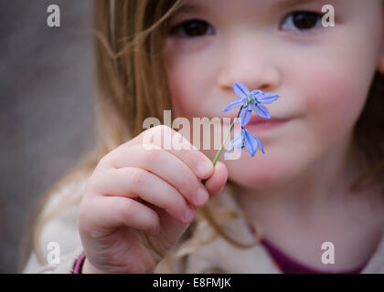 Nahaufnahme eines Mädchens mit einer violetten Blume, England, Großbritannien Stockfoto