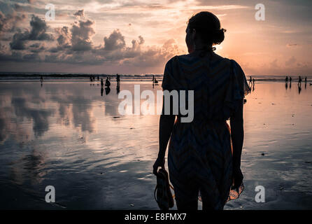 Silhouette der Frau stehen am Strand bei Sonnenuntergang, Legian, Bali, Indonesien Stockfoto