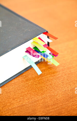 Nahaufnahme eines Hardback-Buches auf einem Tisch mit mehrfarbigen Lesezeichen